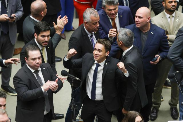 Lawmakers of Brazil's lower house of Congress celebrate after approving a bill that could slash former president Jair Bolsonaro's prison sentence for plotting a coup, in Brasilia on December 10, 2025. The far-right former leader has been serving a 27-year term since November after his conviction for a scheme to stop President Luiz Inacio Lula da Silva from taking office after the 2022 elections. (Photo by Sergio Lima / AFP)