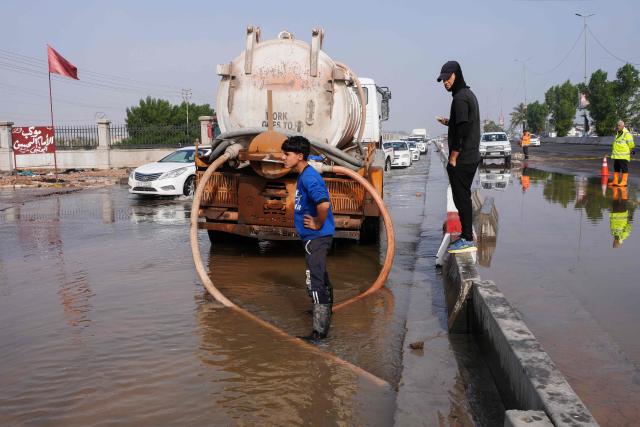 A man clears stagnant water from a flooded road in the northern area of Najaf, in central Iraq, following heavy rains on December 10, 2025. (Photo by Qassem al-KAABI / AFP)