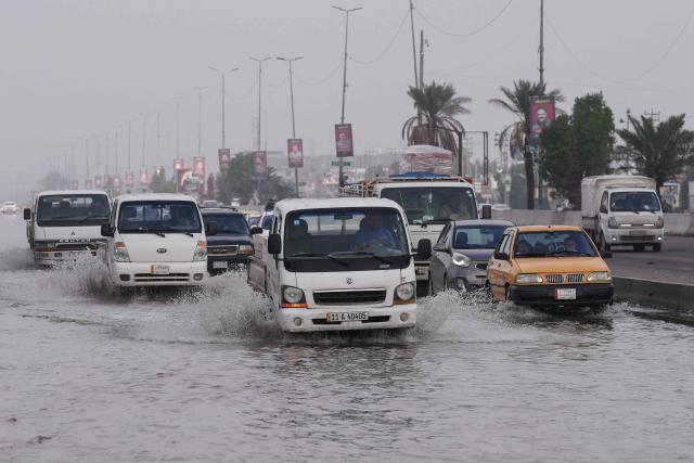 Vehicles drive through a flooded road in the northern area of Najaf, in central Iraq, following heavy rains on December 10, 2025. (Photo by Qassem al-KAABI / AFP)