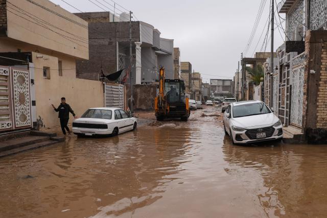 A man makes his way through a flooded street in the northern area of Najaf, in central Iraq, following heavy rains on December 10, 2025. (Photo by Qassem al-KAABI / AFP)