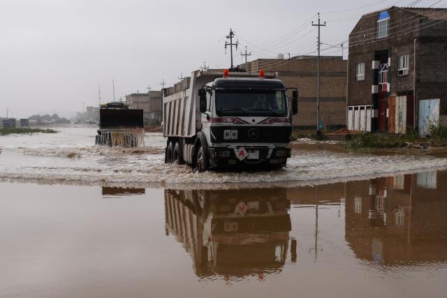 Trucks drive through a flooded road in the northern area of Najaf, in central Iraq, following heavy rains on December 10, 2025. (Photo by Qassem al-KAABI / AFP)
