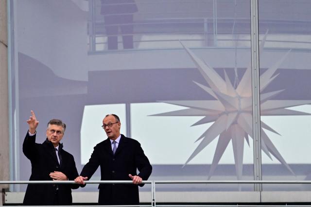 German Chancellor Friedrich Merz (R) and Croatia's Prime Minister Andrej Plenkovic chat as they stand on a balcony of the Chancellery in Berlin on December 10, 2025. (Photo by John MACDOUGALL / AFP)