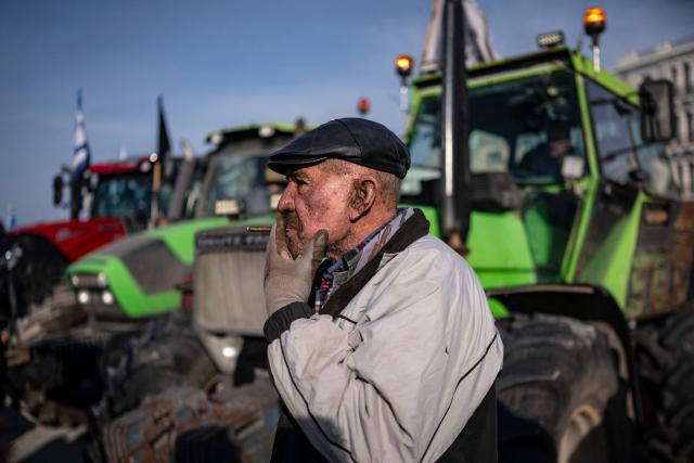 A farmer smokes a cigarillo as he takes part in the blocking of the passengers' port of the central Greek city of Volos during a demonstration on December 10, 2025. Thousands of Greek farmers have since late November 2025 blocked highways, mainly in the centre and north of the country, to demand swifter access to EU subsidies delayed by an ongoing probe into multi-million fraud. (Photo by Aris MESSINIS / AFP)