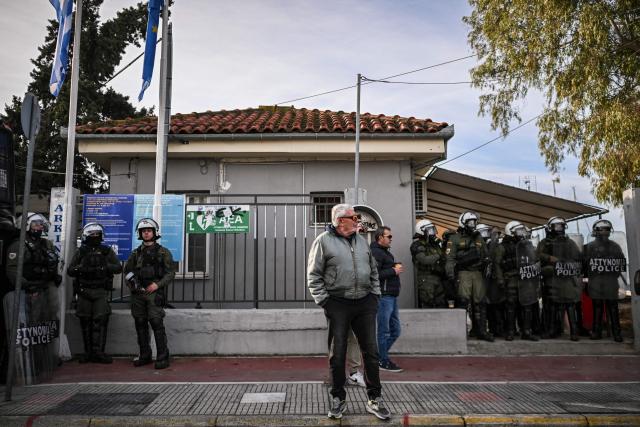 A bystander looks on as farmers take part in the blocking of the passengers' port of the central Greek city of Volos during a demonstration on December 10, 2025. Thousands of Greek farmers have since late November 2025 blocked highways, mainly in the centre and north of the country, to demand swifter access to EU subsidies delayed by an ongoing probe into multi-million fraud. (Photo by Aris MESSINIS / AFP)