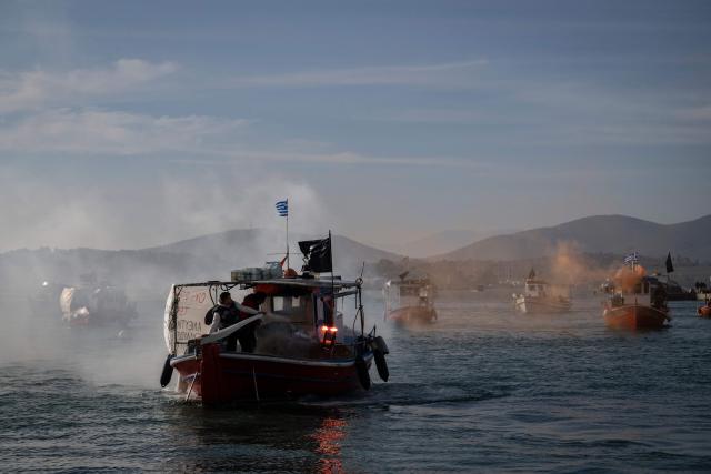 Fishermen light flares and navigate boats to block the passengers' port of the central Greek city of Volos as they take part in a farmers' demonstration on December 10, 2025. Thousands of Greek farmers have since late November 2025 blocked highways, mainly in the centre and north of the country, to demand swifter access to EU subsidies delayed by an ongoing probe into multi-million fraud. (Photo by Aris MESSINIS / AFP)