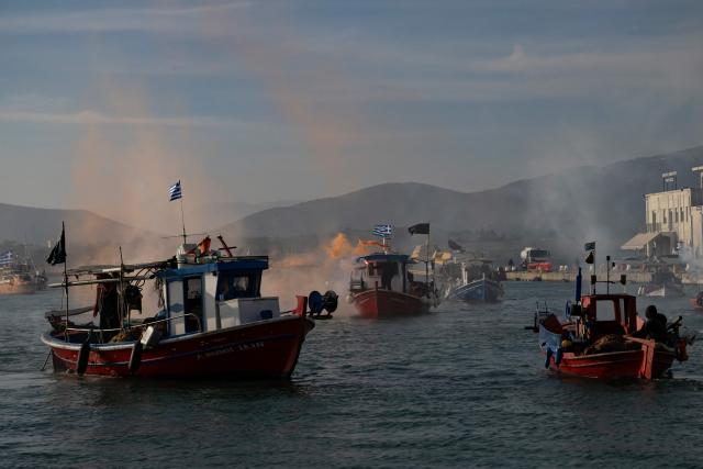 TOPSHOT - Fishermen navigate boats to block the passengers' port of the central Greek city of Volos as they take part in a farmers' demonstration on December 10, 2025. Thousands of Greek farmers have since late November 2025 blocked highways, mainly in the centre and north of the country, to demand swifter access to EU subsidies delayed by an ongoing probe into multi-million fraud. (Photo by Aris MESSINIS / AFP)