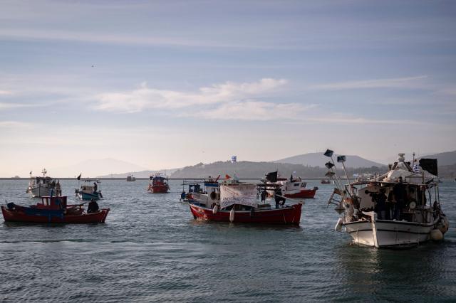 Fishermen navigate boats to block the passengers' port of the central Greek city of Volos as they take part in a farmers' demonstration on December 10, 2025. Thousands of Greek farmers have since late November 2025 blocked highways, mainly in the centre and north of the country, to demand swifter access to EU subsidies delayed by an ongoing probe into multi-million fraud. (Photo by Aris MESSINIS / AFP)