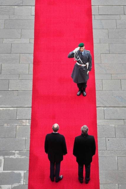 German Chancellor Friedrich Merz (L) and Croatia's Prime Minister Andrej Plenkovic are saluted by a member of the honir guard on the red carpet during a welcoming ceremony in the courtyard of the Chancellery in Berlin on December 10, 2025. (Photo by Markus Schreiber / POOL / AFP)