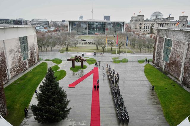 German Chancellor Friedrich Merz (L) and Croatia's Prime Minister Andrej Plenkovic walk along the red carpet as the Reichstag building that houses the Bundestag (lower house of parliament) can be seen in the background (R) during a welcoming ceremony in the courtyard of the Chancellery in Berlin on December 10, 2025. (Photo by Markus Schreiber / POOL / AFP)