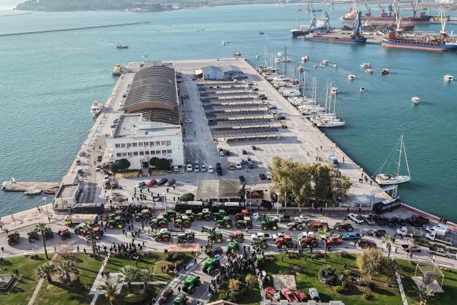 This aerial photograph shows farmers gathered as they take part in the blocking of the passengers' port of the central Greek city of Volos during a demonstration on December 10, 2025. Thousands of Greek farmers have since late November 2025 blocked highways, mainly in the centre and north of the country, to demand swifter access to EU subsidies delayed by an ongoing probe into multi-million fraud. (Photo by Aris MESSINIS / AFP)