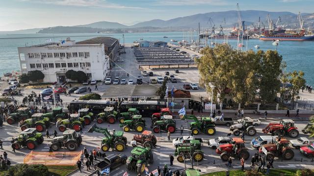 TOPSHOT - This aerial photograph shows farmers gathered as they take part in the blocking of the passengers' port of the central Greek city of Volos during a demonstration on December 10, 2025. Thousands of Greek farmers have since late November 2025 blocked highways, mainly in the centre and north of the country, to demand swifter access to EU subsidies delayed by an ongoing probe into multi-million fraud. (Photo by Aris MESSINIS / AFP)