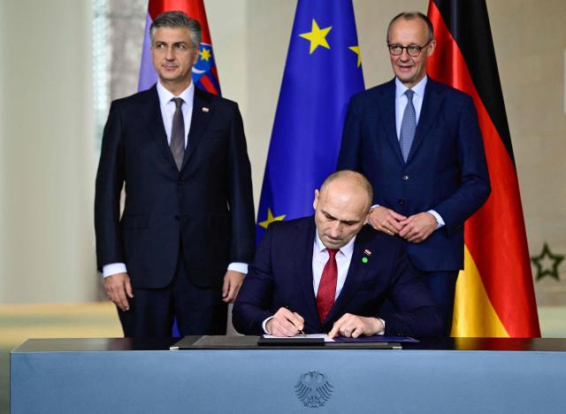 German Chancellor Friedrich Merz (R and Croatia's Prime Minister Andrej Plenkovic look on as Croatia's Defence Minister Ivan Anusic signs a letter of intent at the Chancellery in Berlin on December 10, 2025. (Photo by John MACDOUGALL / AFP)