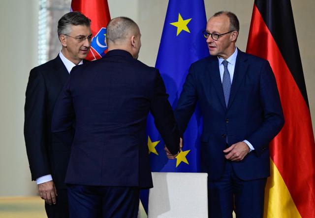 German Chancellor Friedrich Merz (R) and Croatia's Defence Minister Ivan Anusic shake hands as Croatia's Prime Minister Andrej Plenkovic (L) looks on after the signature of a letter of intent at the Chancellery in Berlin on December 10, 2025. (Photo by John MACDOUGALL / AFP)