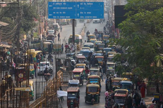 Electric and auto rickshaws commute through traffic along a street in Varanasi on December 10, 2025. (Photo by Niharika KULKARNI / AFP)