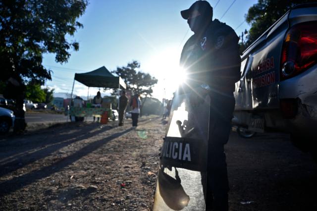 A policeman stands guard outside the facilities of the National Institute of Professional Training (INFOP), where the ballots of the Honduran general elections are being counted, in Tegucigalpa, on December 10, 2025. Honduran President Xiomara Castro on Tuesday denounced what she called tampering with results in the recent general election, and accused US counterpart Donald Trump of interfering in the vote. (Photo by Orlando SIERRA / AFP)