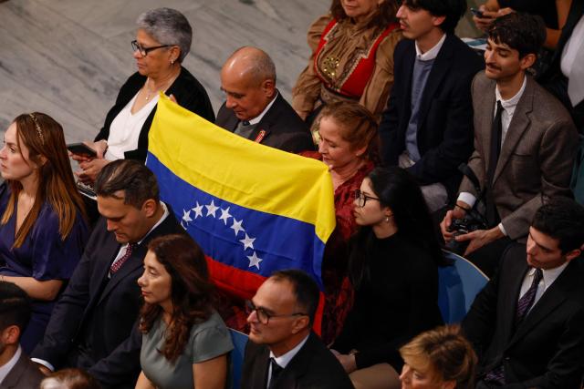 Guests hold up a Venezuelan flag during the Nobel Peace Prize ceremony at Oslo City Hall on December 10, 2025 in Oslo, Norway. The 2025 Nobel Peace Prize was awarded to Machado for her efforts to bring democracy to Venezuela, challenging the iron-fisted rule of Venezuelan President Nicolas Maduro, who has been president since 2013. (Photo by Odd ANDERSEN / NTB / AFP)