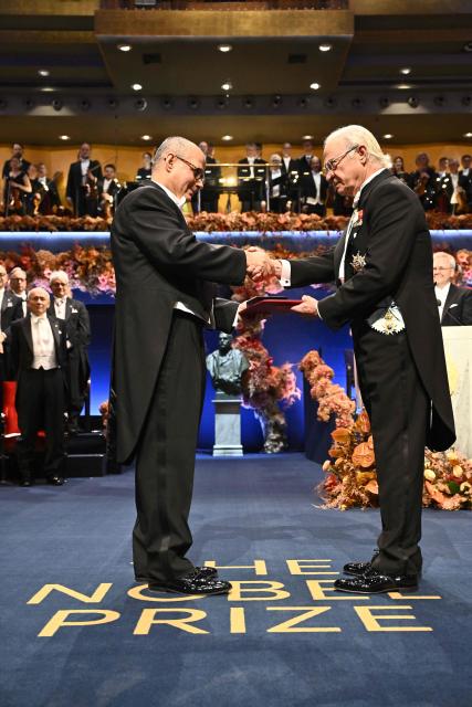 King Carl XVI Gustaf of Sweden (R) hands over the award to Nobel Prize in Chemistry 2025 laureate US-Jordanian chemist Omar M. Yaghi during the award ceremony on December 10, 2025 in Stockholm, Sweden. The laureates received their prizes at formal ceremonies in Stockholm and Oslo on December 10. That date is the anniversary of the death in 1896 of scientist Alfred Nobel, who created the prizes in his will. (Photo by Henrik Montgomery/TT / TT NEWS AGENCY / AFP) / Sweden OUT