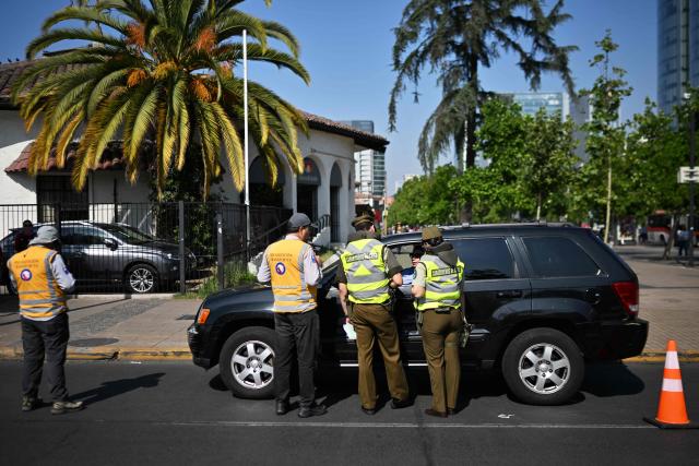 A police officers check the ID of a driver during a joint operation with private security from Las Condes municipality in Santiago on December 10, 2025. The second round of the Chilean presidential election on December 14 will pit two candidates against each other who are diametrically opposed: Jeannette Jara, the representative of a broad left-wing coalition with modest origins, and the far-right leader Jose Antonio Kast, an ultraconservative Catholic determined to massively expel undocumented migrants. (Photo by Rodrigo ARANGUA / AFP)