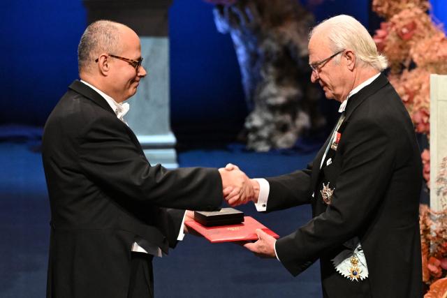 King Carl XVI Gustaf of Sweden (R) shakes hands after handing over the award to Nobel Prize in Chemistry 2025 laureate US-Jordanian chemist Omar M. Yaghi during the award ceremony on December 10, 2025 in Stockholm, Sweden. The laureates received their prizes at formal ceremonies in Stockholm and Oslo on December 10. That date is the anniversary of the death in 1896 of scientist Alfred Nobel, who created the prizes in his will. (Photo by Jonathan Nackstrand / AFP)