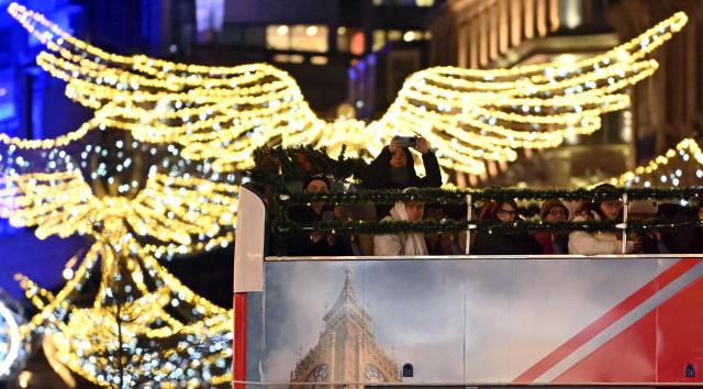 People travelling on an open-top bus tour look at the annual Christmas lights on Regent Street, in central London, on December 10, 2025. (Photo by JUSTIN TALLIS / AFP)