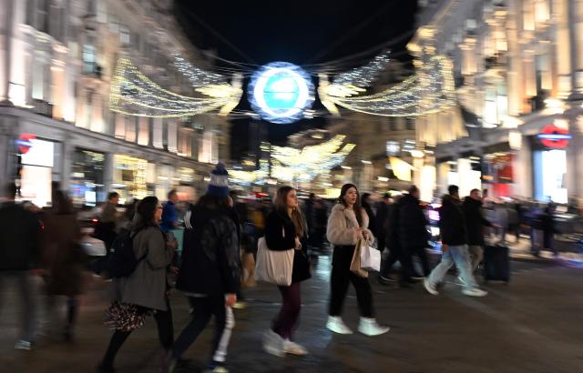 People pass beneath the annual Christmas lights as they cross Oxford Street, in central London, on December 10, 2025. (Photo by JUSTIN TALLIS / AFP)