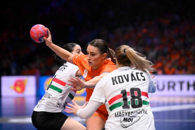 Netherlands' centre back #09 Larissa Nusser (C) is blocked by Hungary's right wing #18 Anett Kovacs (R) during the quarter finals match between the Netherlands and Hungary of the IHF Women's Handball World Championship in Rotterdam Ahoy, in Rotterdam on December 10, 2025. (Photo by JOHN THYS / AFP)