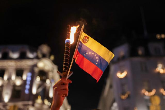 A participant holds a torch and a flag of Venezuela as people attend a torchlight procession organises by the Norwegian Venezuelan Justice Alliance in honor of Nobel Peace Prize laureate Maria Corina Machado in Oslo, Norway, on December 10, 2025. The daughter of the Nobel Peace Prize laureate, Ana Corina Sosa, accepted the award on behalf of her mother during a ceremony at Oslo City Hall. Venezuelan opposition leader Maria Corina Machado received the award for her tireless work to secure democratic rights for the people of Venezuela, and for her fight for a just and peaceful transition from dictatorship to popular rule. Due to the circumstances in her home country of Venezuela, the Nobel Peace Prize laureate was unable to attend the award ceremony in Norway. (Photo by Amanda Pedersen Giske / NTB / AFP) / Norway OUT