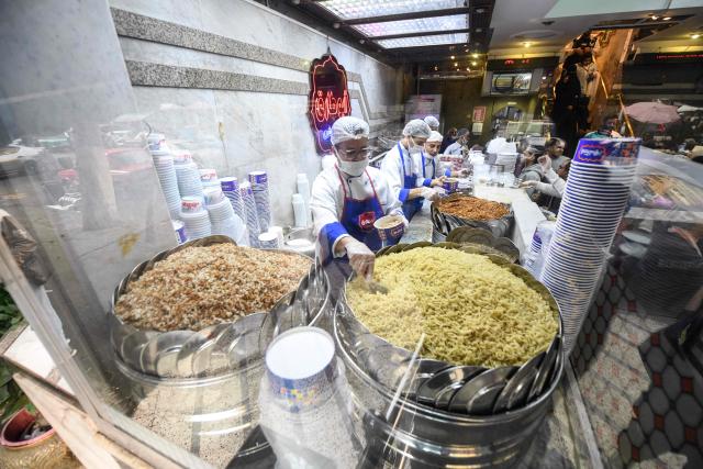 Egyptian chefs prepare a traditional dish in Arabic known as Koshary at Abou Tarek restaurant downtown Cairo on December 10, 2025. UNESCO recognised December 10 Egypt's favourite daily dish as intangible cultural heritage, to the delight of Egyptians digging into the spicy staple at every corner. (Photo by Ahmed HASAN / AFP)