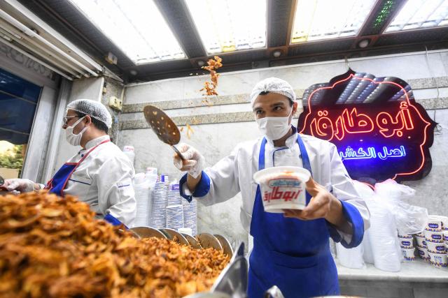 An Egyptian chef prepares a traditional dish in Arabic known as Koshary at Abou Tarek restaurant downtown Cairo on December 10, 2025. UNESCO recognised December 10 Egypt's favourite daily dish as intangible cultural heritage, to the delight of Egyptians digging into the spicy staple at every corner. (Photo by Ahmed HASAN / AFP)