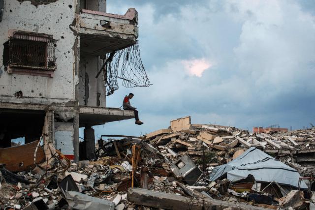 TOPSHOT - A man sits on the edge a destroyed building in the Al-Saftawi neighborhood, west of Jabalia city in the northern Gaza Strip on December 10, 2025. (Photo by BASHAR TALEB / AFP)