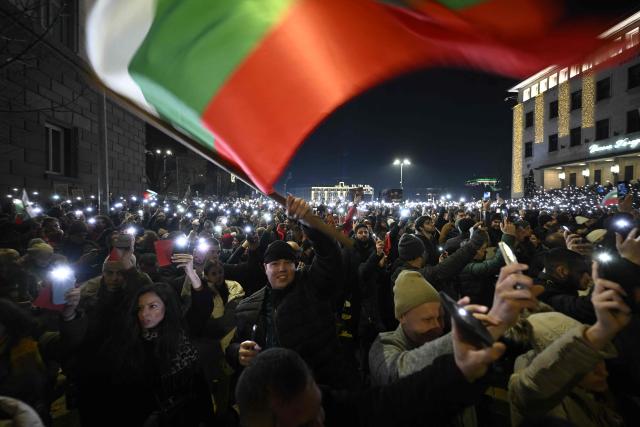 A protester waves the Bulgarian flag during an anti-government protest in Sofia on December 10, 2025. Tens of thousands of people held anti-government protests in Bulgaria on Monday, widening an anti-corruption movement sweeping the European Union's poorest country as it prepares to adopt the euro. (Photo by DIMITAR KYOSEMARLIEV / AFP)