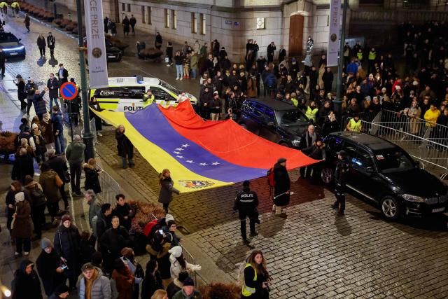 People hold a Venezualian flag as they take part in a torchlight procession organized by The Norwegian Venezuelan Justice Alliance in honor of Nobel Peace Prize laureate Maria Corina Machado in Oslo, Norway, on December 10, 2025. The daughter of the Nobel Peace Prize laureate, Ana Corina Sosa, accepted the award on behalf of her mother during a ceremony at Oslo City Hall. Venezuelan opposition leader Maria Corina Machado received the award for her tireless work to secure democratic rights for the people of Venezuela, and for her fight for a just and peaceful transition from dictatorship to popular rule. Due to the circumstances in her home country of Venezuela, the Nobel Peace Prize laureate was unable to attend the award ceremony in Norway. (Photo by Jonas Been Henriksen / NTB / AFP) / Norway OUT