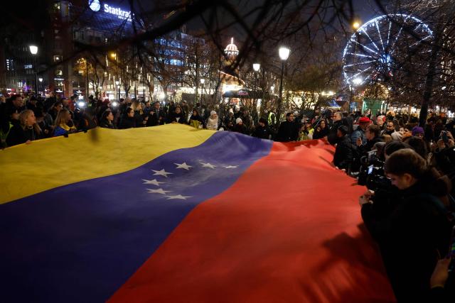 People hold a Venezualian flag as they take part in a torchlight procession organized by The Norwegian Venezuelan Justice Alliance in honor of Nobel Peace Prize laureate Maria Corina Machado in Oslo, Norway, on December 10, 2025. The daughter of the Nobel Peace Prize laureate, Ana Corina Sosa, accepted the award on behalf of her mother during a ceremony at Oslo City Hall. Venezuelan opposition leader Maria Corina Machado received the award for her tireless work to secure democratic rights for the people of Venezuela, and for her fight for a just and peaceful transition from dictatorship to popular rule. Due to the circumstances in her home country of Venezuela, the Nobel Peace Prize laureate was unable to attend the award ceremony in Norway. (Photo by Odd ANDERSEN / AFP) / Norway OUT