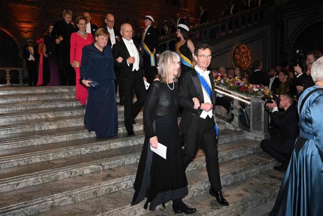 Sweden's Prime Minister Ulf Kristersson (R) followed by German former Chancellor Angela Merkel, arrives to attend the Nobel Prize banquet on December 10, 2025 at the City Hall in Stockholm, Sweden. The laureates received their prizes at formal ceremonies in Stockholm and Oslo on December 10. That date is the anniversary of the death in 1896 of scientist Alfred Nobel, who created the prizes in his will. (Photo by Jonathan Nackstrand / AFP)