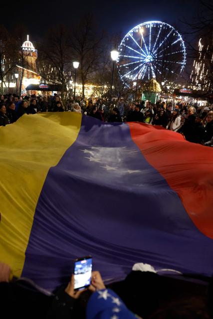 People hold a Venezualian flag as they take part in a torchlight procession organized by The Norwegian Venezuelan Justice Alliance in honor of Nobel Peace Prize laureate Maria Corina Machado in Oslo, Norway, on December 10, 2025. The daughter of the Nobel Peace Prize laureate, Ana Corina Sosa, accepted the award on behalf of her mother during a ceremony at Oslo City Hall. Venezuelan opposition leader Maria Corina Machado received the award for her tireless work to secure democratic rights for the people of Venezuela, and for her fight for a just and peaceful transition from dictatorship to popular rule. Due to the circumstances in her home country of Venezuela, the Nobel Peace Prize laureate was unable to attend the award ceremony in Norway. (Photo by Odd ANDERSEN / AFP) / Norway OUT