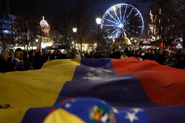 TOPSHOT - People hold a Venezualian flag as they take part in a torchlight procession organized by The Norwegian Venezuelan Justice Alliance in honor of Nobel Peace Prize laureate Maria Corina Machado in Oslo, Norway, on December 10, 2025. The daughter of the Nobel Peace Prize laureate, Ana Corina Sosa, accepted the award on behalf of her mother during a ceremony at Oslo City Hall. Venezuelan opposition leader Maria Corina Machado received the award for her tireless work to secure democratic rights for the people of Venezuela, and for her fight for a just and peaceful transition from dictatorship to popular rule. Due to the circumstances in her home country of Venezuela, the Nobel Peace Prize laureate was unable to attend the award ceremony in Norway. (Photo by Odd ANDERSEN / AFP) / Norway OUT
