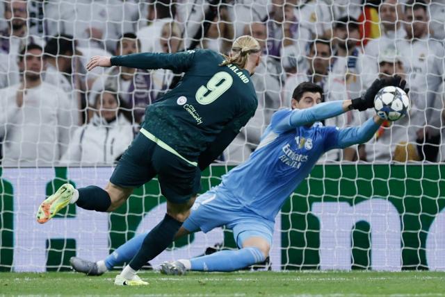 Real Madrid's Belgian goalkeeper #01 Thibaut Courtois (R) makes a save from a shot on goal by Manchester City's Norwegian forward #09 Erling Braut Haland during the UEFA Champions League league phase day 6 football match between Real Madrid CF and Manchester City at Santiago Bernabeu Stadium in Madrid on December 10, 2025. (Photo by Oscar DEL POZO / AFP)