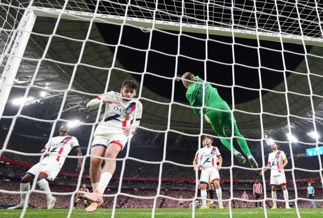 Paris Saint-Germain's Russian goalkeeper #39 Matvey Safonov jumps for the ball next to Paris Saint-Germain's Georgian forward #07 Khvicha Kvaratskhelia during the UEFA Champions League league phase day 6 football match between Athletic Club Bilbao and Paris Saint-Germain (PSG) at San Mames Stadium in Bilbao on December 10, 2025. (Photo by CESAR MANSO / AFP)