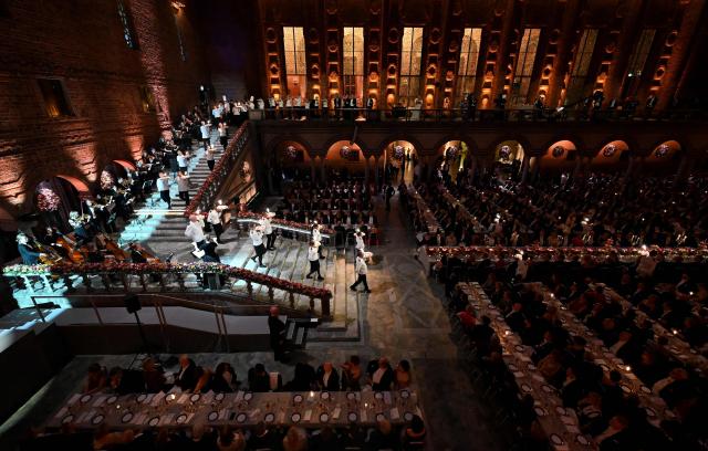 Waiters arrive to serve the dessert during the Nobel Prize banquet on December 10, 2025 at the City Hall in Stockholm, Sweden. The laureates received their prizes at formal ceremonies in Stockholm and Oslo on December 10. That date is the anniversary of the death in 1896 of scientist Alfred Nobel, who created the prizes in his will. (Photo by Jonathan Nackstrand / AFP)