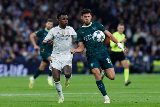 Real Madrid's Brazilian forward #07 Vinicius Junior (L) and Manchester City's Portuguese midfielder #27 Matheus Nunes vie for the ball during the UEFA Champions League league phase day 6 football match between Real Madrid CF and Manchester City at Santiago Bernabeu Stadium in Madrid on December 10, 2025. (Photo by Oscar DEL POZO / AFP)