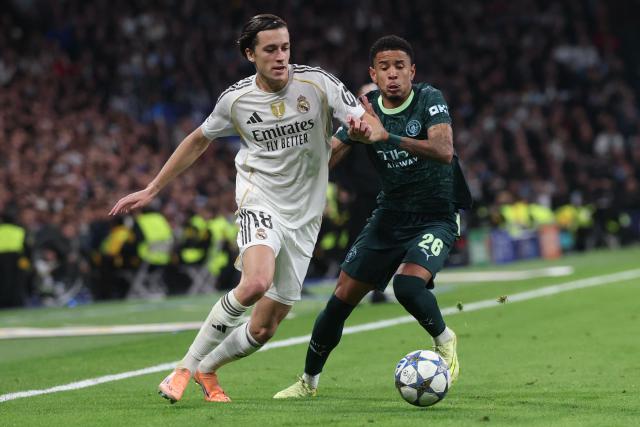 Real Madrid's Spanish defender #18 Alvaro Carreras (L) vies for the ball  with Manchester City's Brazilian forward #26 Savio Moreira De Oliveira during the UEFA Champions League league phase day 6 football match between Real Madrid CF and Manchester City at Santiago Bernabeu Stadium in Madrid on December 10, 2025. (Photo by Pierre-Philippe MARCOU / AFP)