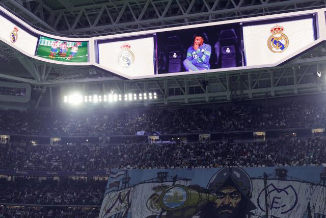 Real Madrid's French forward #10 Kylian Mbappe appears on a giant screen while sitting on the bench during the UEFA Champions League league phase day 6 football match between Real Madrid CF and Manchester City at Santiago Bernabeu Stadium in Madrid on December 10, 2025. (Photo by Oscar DEL POZO / AFP)