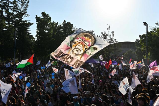 Supporters of Chile's presidential candidate Jeannette Jara, of the Unidad por Chile coalition, wave flags ahead of her closing campaign rally in Santiago on December 10, 2025. The second round of the Chilean presidential election on December 14 will pit two candidates against each other who are diametrically opposed: Jeannette Jara, the representative of a broad left-wing coalition with modest origins, and the far-right leader Jose Antonio Kast, an ultraconservative Catholic determined to massively expel undocumented migrants. (Photo by Rodrigo ARANGUA / AFP)