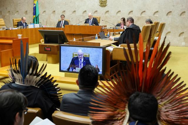Brazil's Chief Justice Edson Fachin (C) speaks during a session in which Supreme Court judges discuss the so-called "Time Framework" legal thesis regarding the demarcation of Indigenous lands, in Brasilia on December 10, 2025. Brazil's Supreme Court started deliberations on a law restricting the demarcation of indigenous lands, which protection is crucial in the fight against global warming. (Photo by Sergio Lima / AFP)