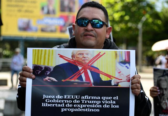 A demonstrator holds a sign crossing out US President Donald Trump in Medellin, Colombia on December 10, 2025. (Photo by JAIME SALDARRIAGA / AFP)