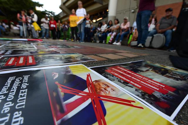 People demonstrate past a sign crossing out US President Donald Trump in Medellin, Colombia on December 10, 2025. (Photo by JAIME SALDARRIAGA / AFP)