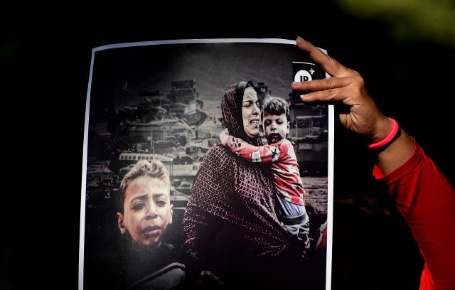 A demonstrator holds a sign depicting a family during the war, in Medellin, Colombia on December 10, 2025. (Photo by JAIME SALDARRIAGA / AFP)
