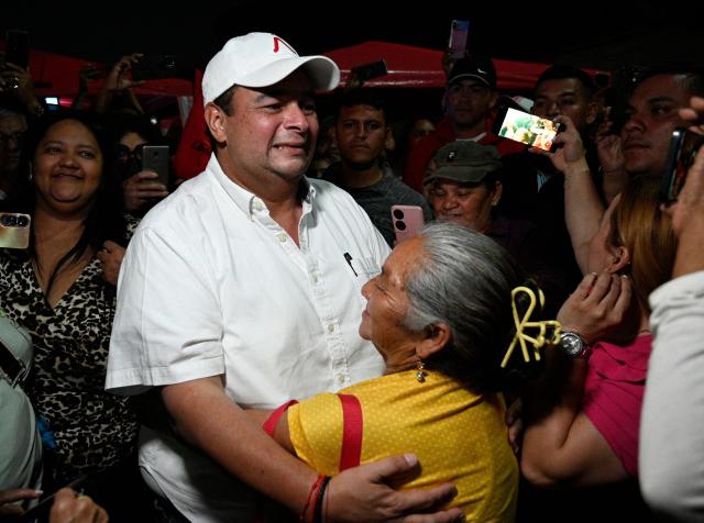 Tegucigalpa's mayor and incumbent candidate Jorge Aldana dances with a ruling Libertad y Refundacion (LIBRE) party supporter at the Professional Formation National Institute headquarters, where the electoral material for last presidential election is being held, in Tegucigalpa on December 10, 2025. The Honduran military vowed on December 10, 2025, to ensure a peaceful transfer of power regardless of who wins a November 30 presidential election in which votes are still being counted amid interference claims. (Photo by Orlando SIERRA / AFP)