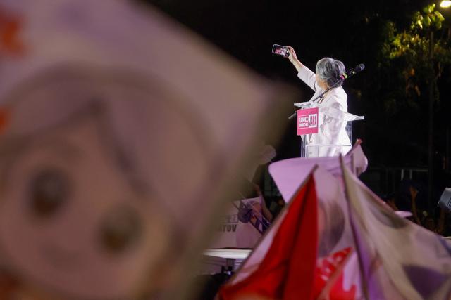 Chile's presidential candidate Jeannette Jara of the Unidad por Chile coalition takes a photo with her mobile phone during her closing campaign rally in Santiago on December 10, 2025. The second round of the Chilean presidential election on December 14 will pit two candidates against each other who are diametrically opposed: Jeannette Jara, the representative of a broad left-wing coalition with modest origins, and the far-right leader Jose Antonio Kast, an ultraconservative Catholic determined to massively expel undocumented migrants. (Photo by Raul BRAVO / AFP)
