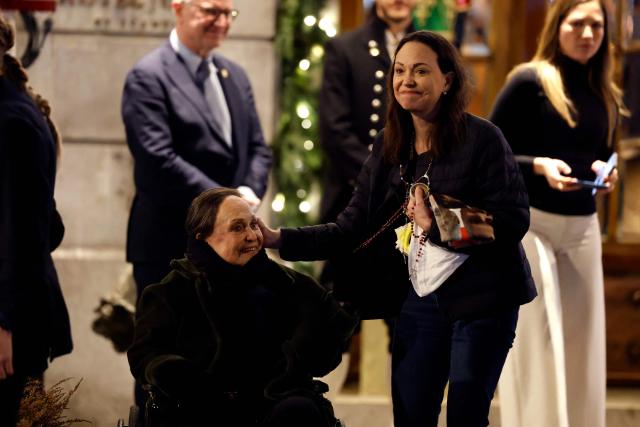 Nobel peace laureate Maria Corina Machado (R) caresses her mother Corina Parisca Perez as she greets supporters gathered outside the Grand Hotel in Oslo, Norway, in the early hours of December 11, 2025. Machado arrived in Oslo hours after the Venezuelan opposition leader's award was collected on her behalf by her daughter. (Photo by Odd ANDERSEN / AFP)